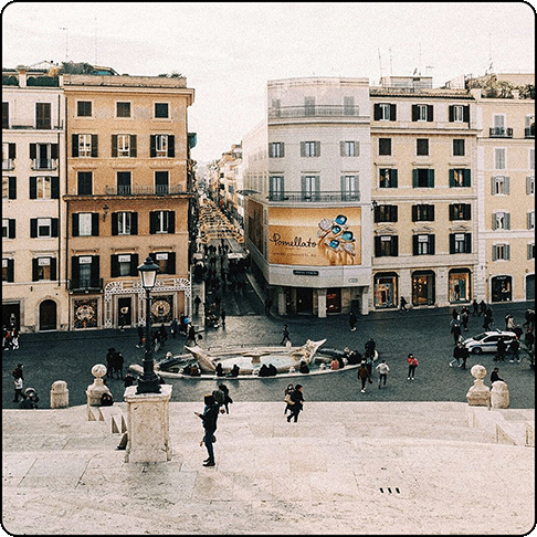 Image Description: Open plaza with large fountain in the center and marble steps. Old European-style buildings in the background.
