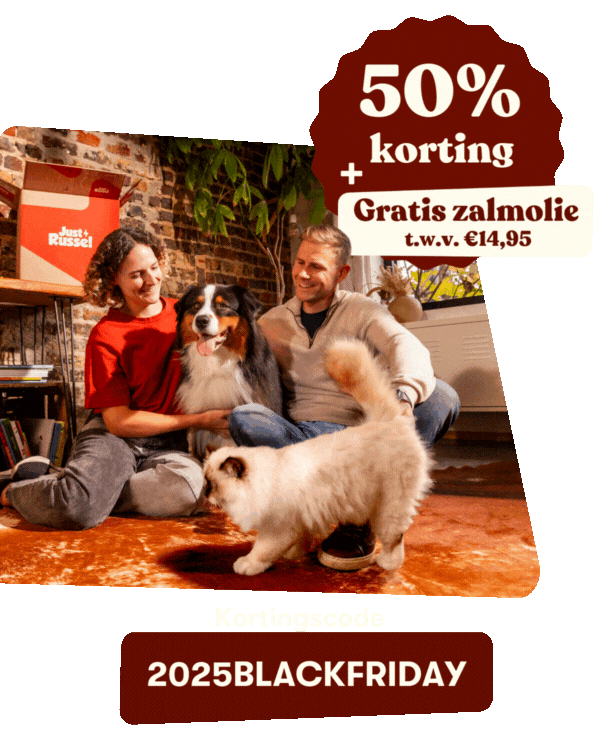 Een vrouw staat lachend in de keuken tussen haar hond en kat. Op het aanrecht staan zakken dierenvoer en een Just Russel-doos. Tekst: “35% korting + gratis zalmolie t.w.v. €14,95. Kortingscode BLACKFRIDAY2025.”