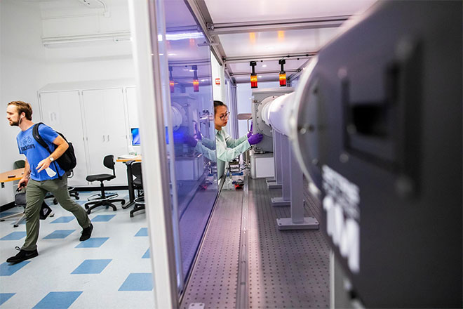 A worker examines a piece of machinery in a life sciences lab.