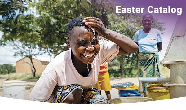 A girl smiles and splashes clean water on her face.