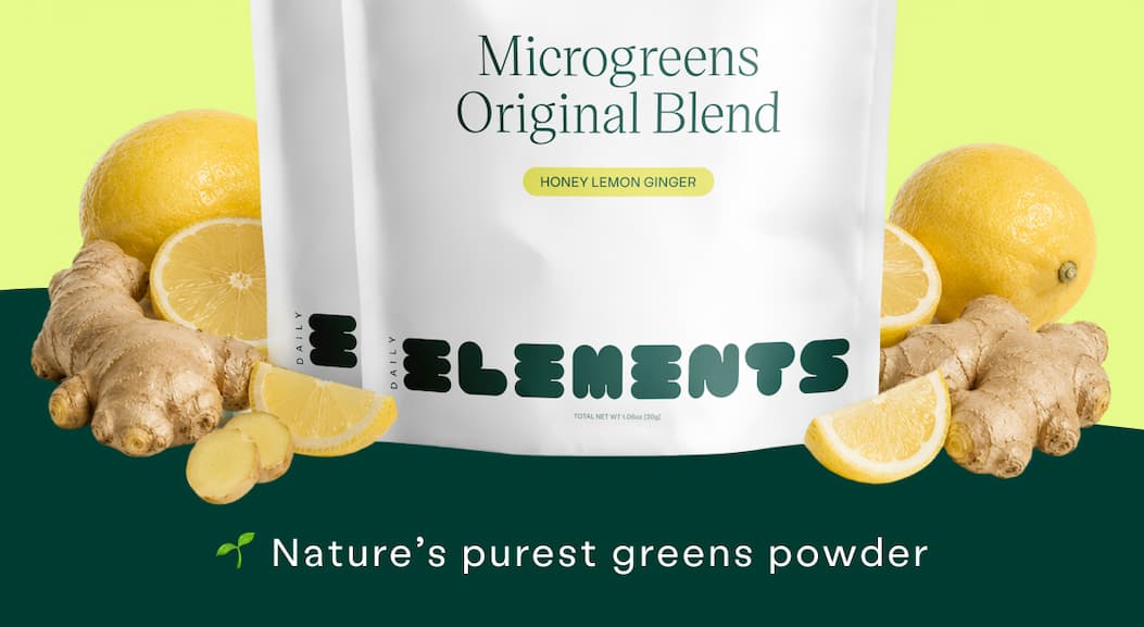 Daily Elements Microgreens Original Blend in Honey Lemon Ginger surrounded by fresh lemons and ginger. Nature's purest greens powder