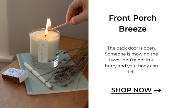 image of someone lighting front porch breeze candle on a journal with a pen and lavender
