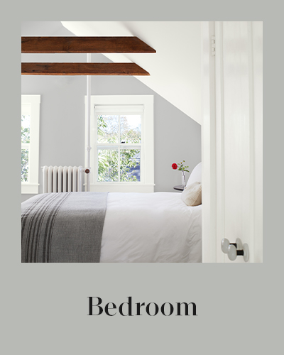 A gray painted bedroom wall with white trim and a white vaulted ceiling.