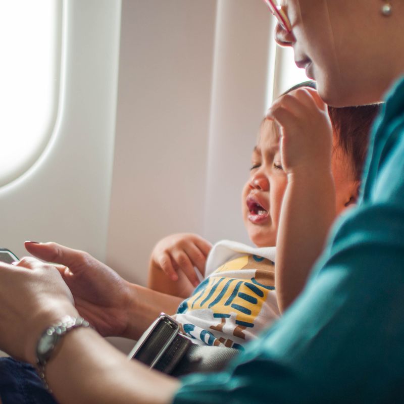 Crying baby on mother's lap on the plane