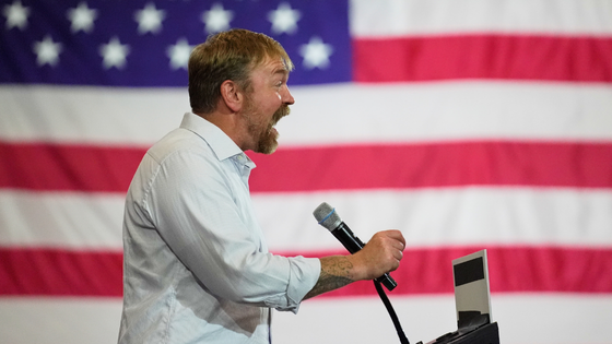 A man stands against an American flag.
