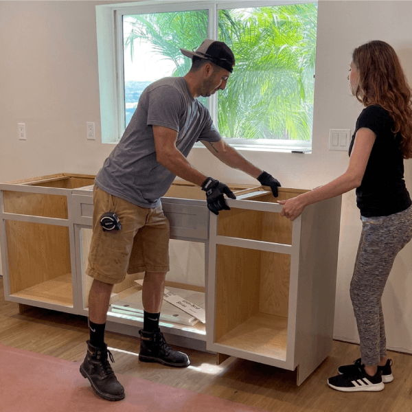 Two people assembling kitchen cabinets.