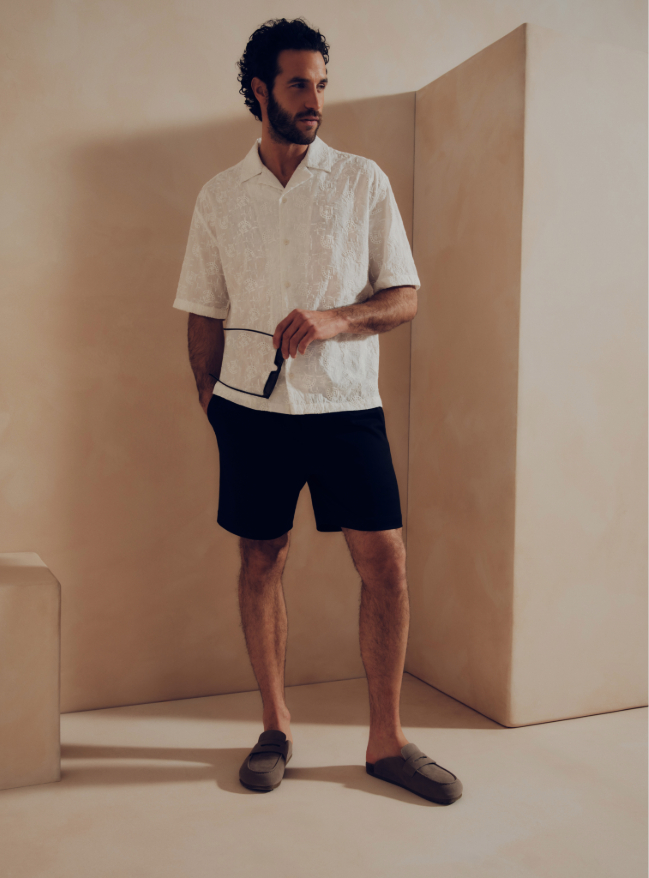 A man wearing an Embroidered Cotton Short Sleeve Shirt and blue shorts