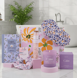 Hamper of purple-coloured items in a bathroom, including a candle, tea, an eyemask and a scrunchie