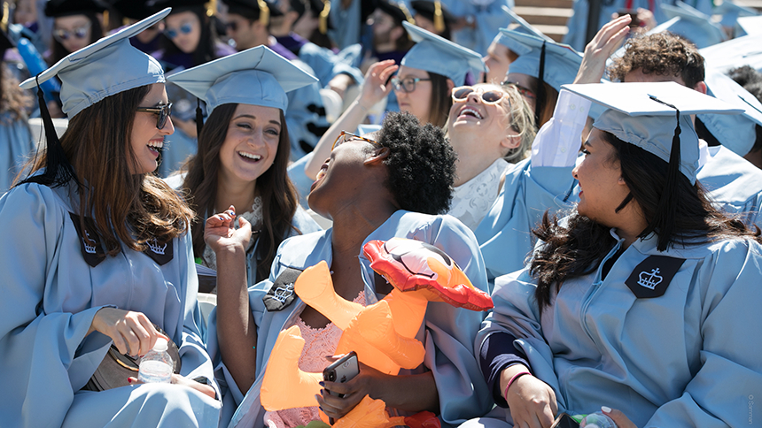 Graduates sitting at Commencement and laughing with each other