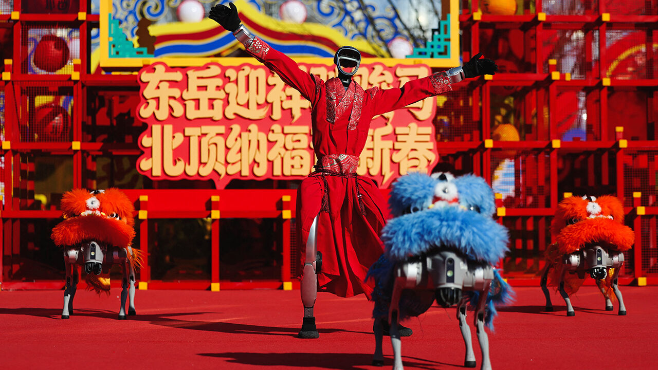 A humanoid robot performs a dance with robot dogs dressed in lion costumes 