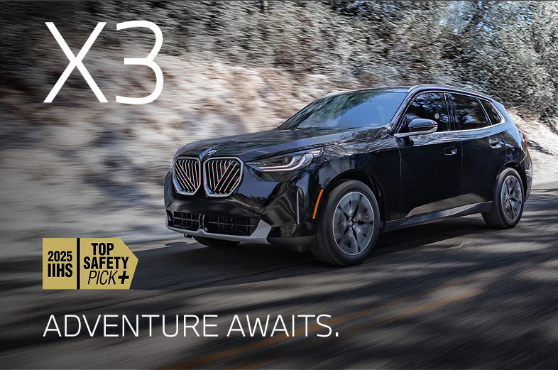 2026 BMW X3 driving down a winter road with snowy trees in the background