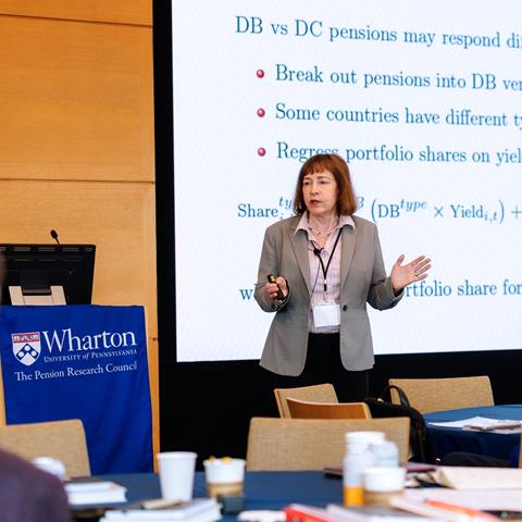 A speaker presents in front of a screen