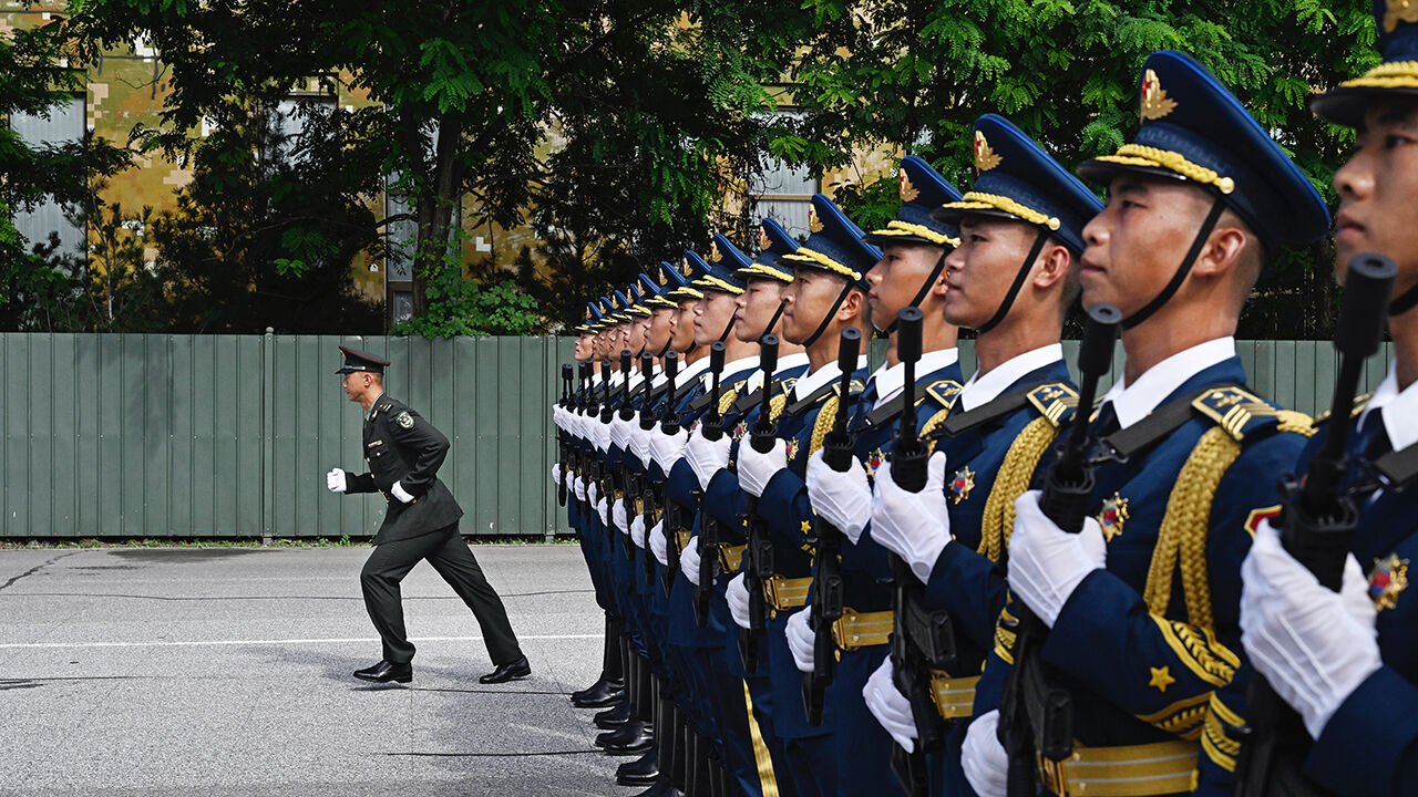 An officer runs back to his position after correcting soldiers from the People's Liberation Army as they march in formation during a  practice for an upcoming military parade