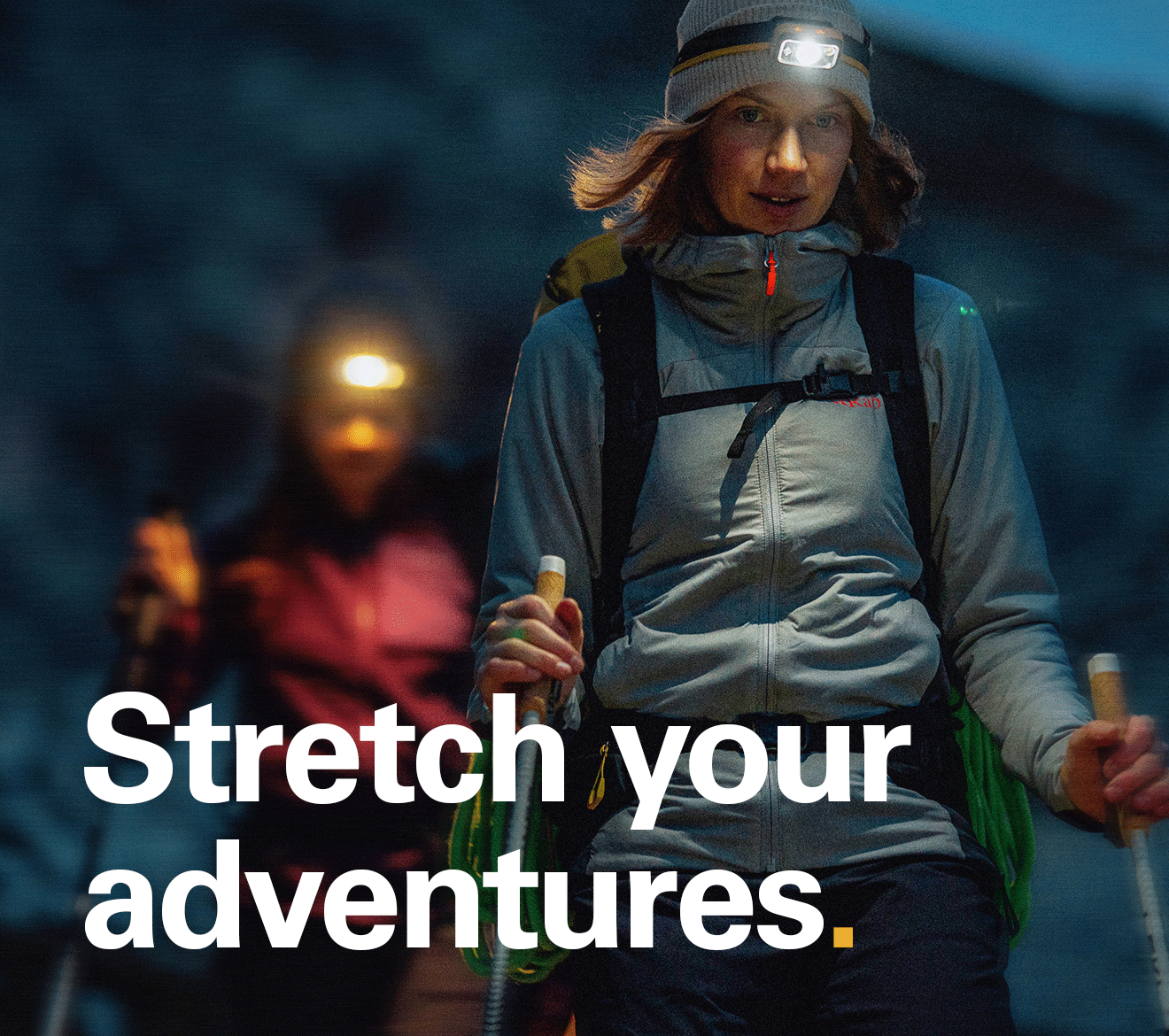 'Stretch your adventures.' Text over the image of 2 people out on a hike in the evening.