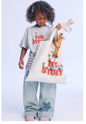 Child wearing Toy Story graphic tee and patterned jeans with toy.
