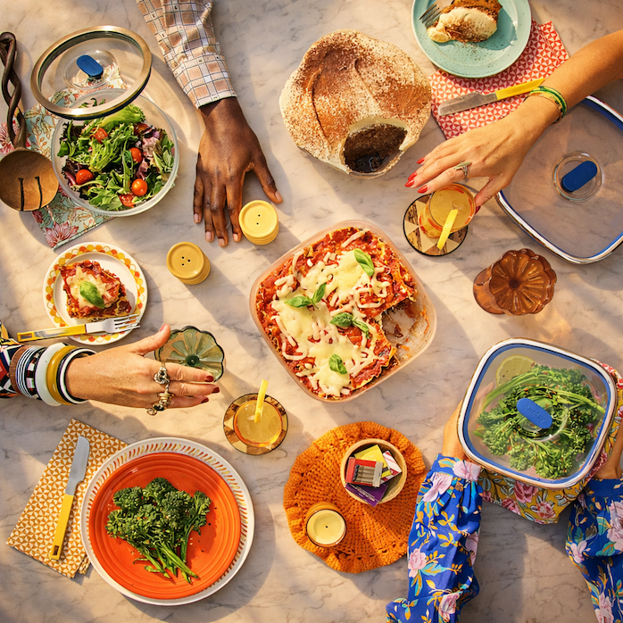 A table full of Anyday dishes with multiple hands serving themselves