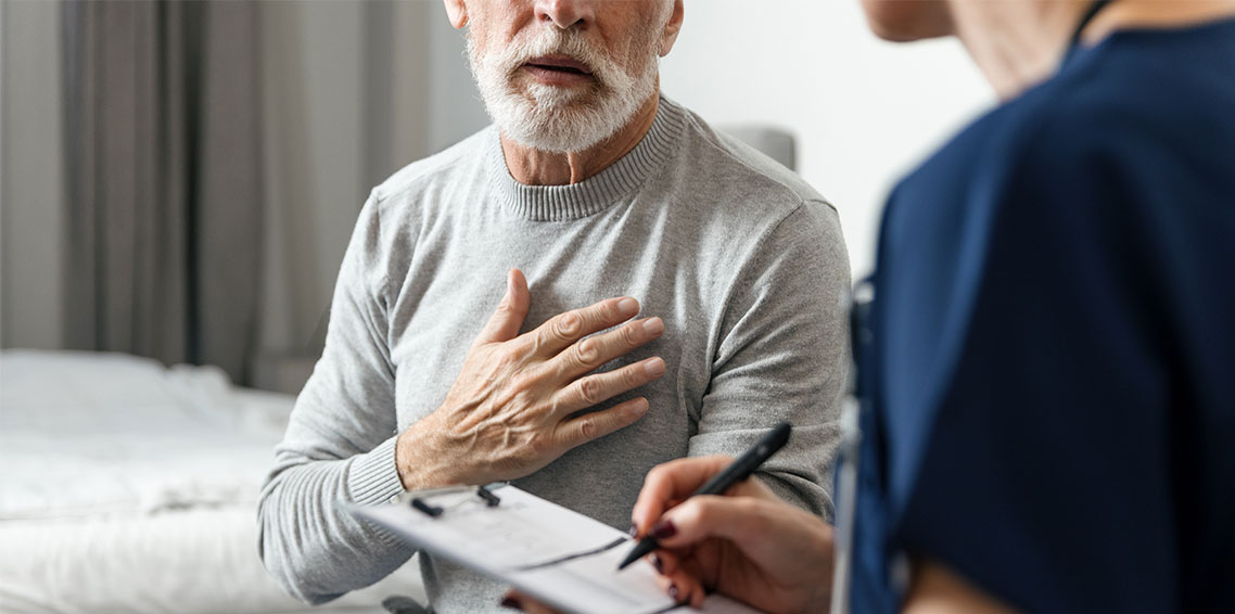  An older man speaks to a doctor with his hand over his heart.