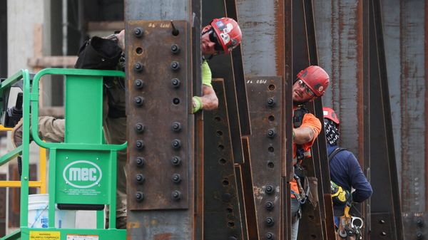 Steel workers climb around girders as construction work continues on the US Federal Reserve building campus in Washington, DC, USA.