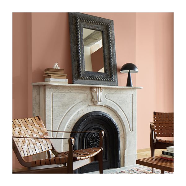 A pink painted parlor with a fireplace and chairs.